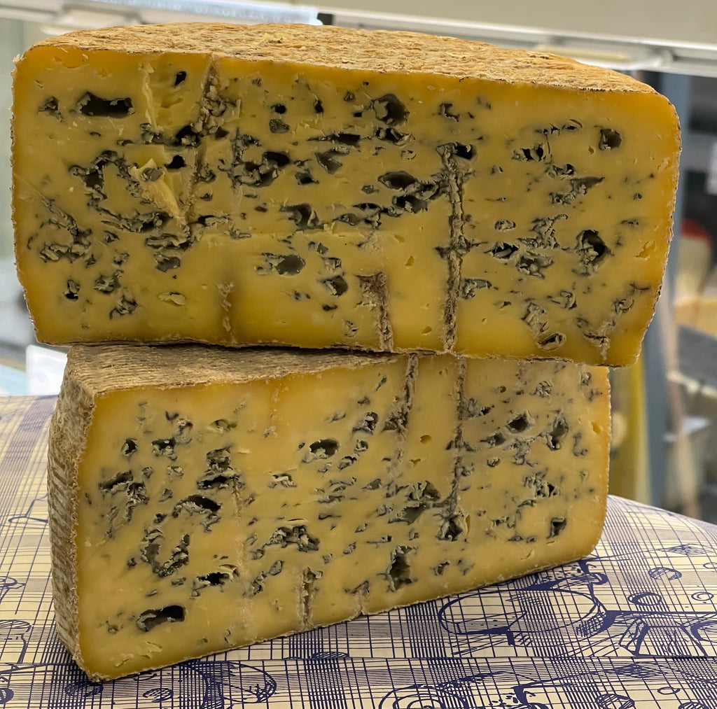Two blocks of blue cheese stacked on a patterned tablecloth